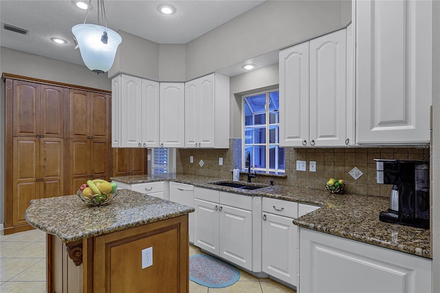 kitchen featuring light tile patterned floors, visible vents, a sink, and dark stone countertops