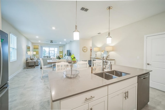 kitchen with pendant lighting, sink, a kitchen island with sink, white cabinetry, and appliances with stainless steel finishes