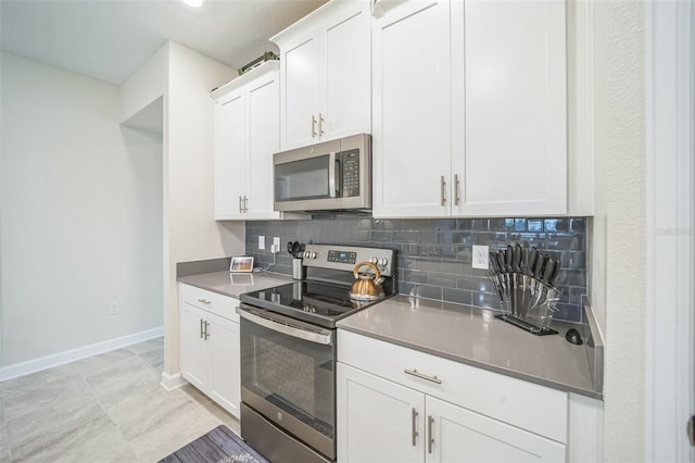 kitchen with white cabinets, stainless steel appliances, light tile patterned floors, and backsplash