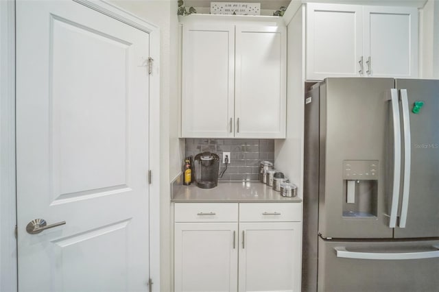 kitchen featuring white cabinetry, decorative backsplash, and stainless steel fridge