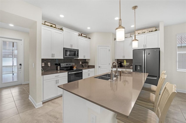 kitchen featuring an island with sink, stainless steel appliances, pendant lighting, and a breakfast bar