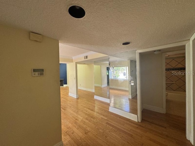 hallway with wood-type flooring, a textured ceiling, and an inviting chandelier