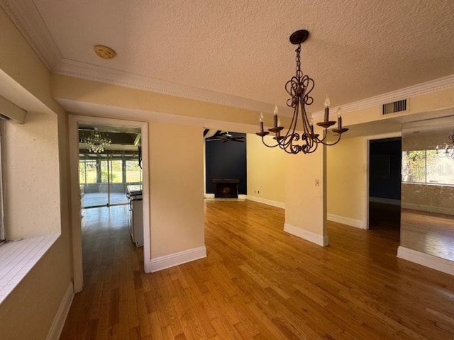 unfurnished dining area featuring a textured ceiling, wood-type flooring, ornamental molding, and plenty of natural light