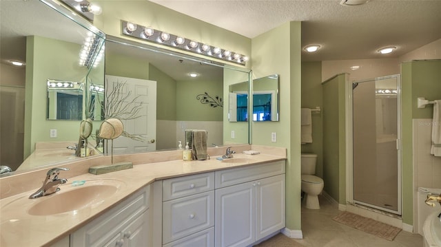 bathroom featuring a shower with door, vanity, a textured ceiling, tile patterned flooring, and toilet