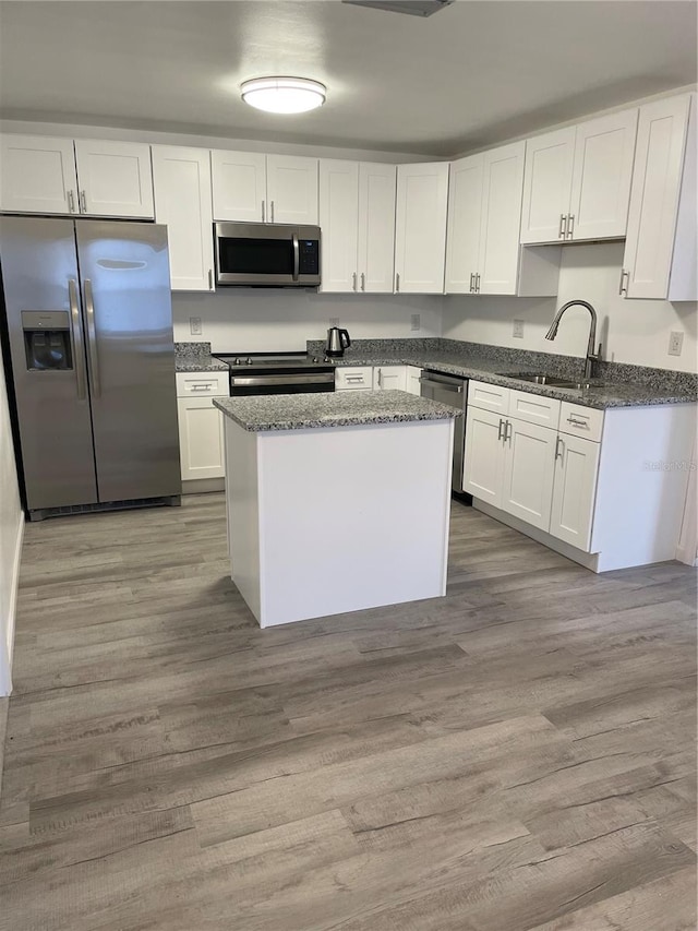 kitchen with stainless steel appliances, white cabinets, and light wood-type flooring