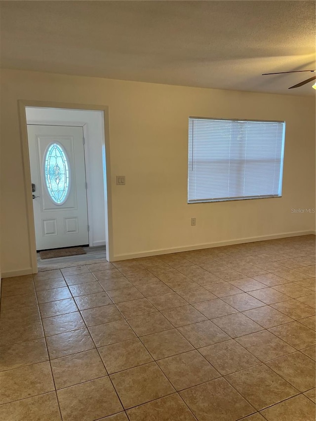 tiled foyer entrance featuring a textured ceiling and ceiling fan