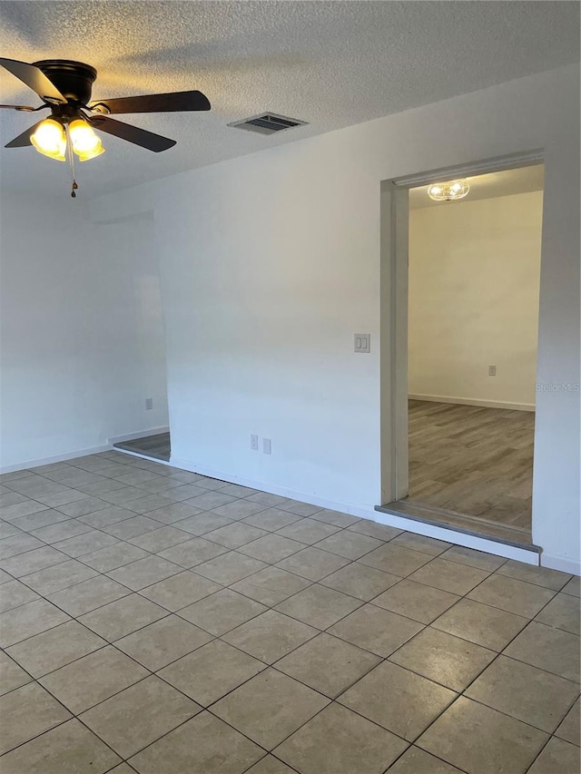 unfurnished room with a textured ceiling, ceiling fan, and light tile patterned floors