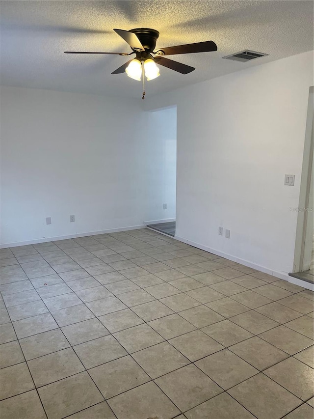 tiled empty room featuring a textured ceiling and ceiling fan