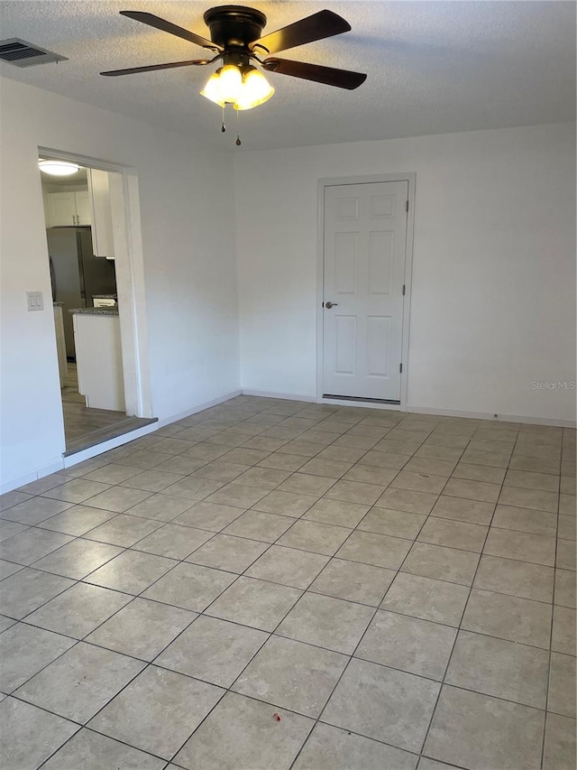 unfurnished room with ceiling fan, a textured ceiling, and light tile patterned floors