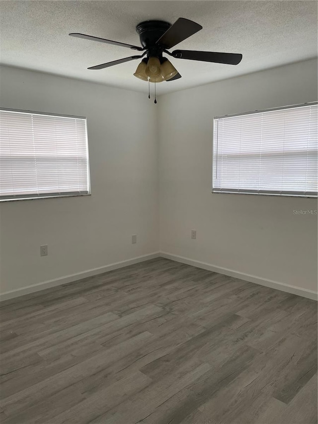 spare room with a textured ceiling, dark hardwood / wood-style flooring, and ceiling fan