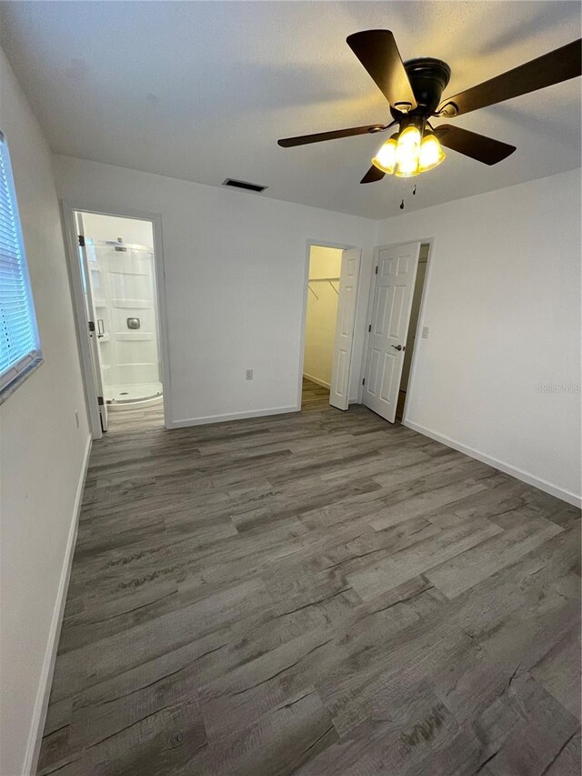 unfurnished bedroom featuring a closet, a spacious closet, hardwood / wood-style flooring, ceiling fan, and ensuite bathroom