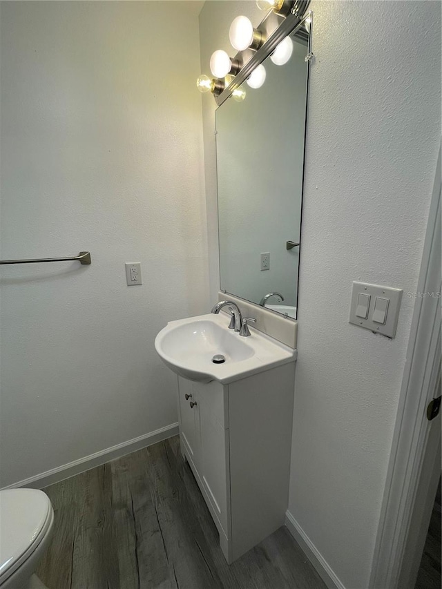 bathroom with hardwood / wood-style floors, vanity, and toilet