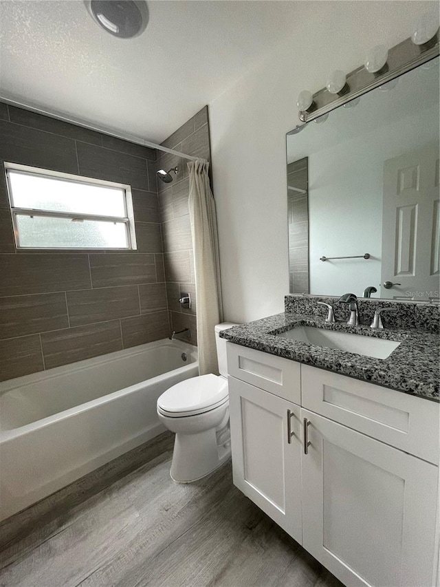 full bathroom with hardwood / wood-style floors, shower / tub combo with curtain, vanity, and toilet