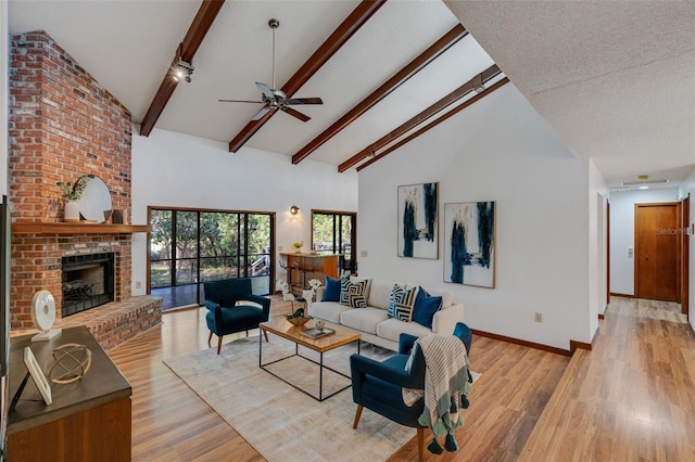 living room featuring high vaulted ceiling, light hardwood / wood-style floors, a textured ceiling, and a brick fireplace