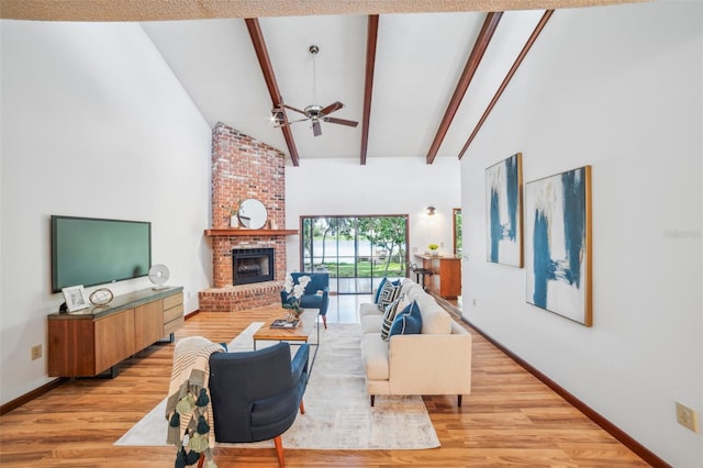 living room featuring high vaulted ceiling, ceiling fan, beam ceiling, a fireplace, and light hardwood / wood-style floors