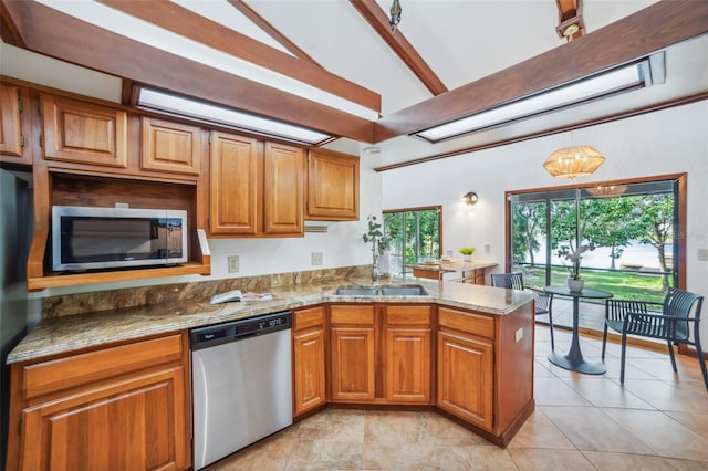 kitchen featuring kitchen peninsula, light stone counters, stainless steel appliances, sink, and lofted ceiling with beams