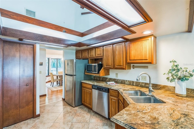 kitchen featuring light stone counters, light wood-type flooring, sink, and appliances with stainless steel finishes