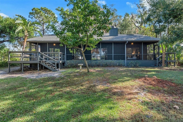 rear view of house featuring a sunroom, a yard, and a deck