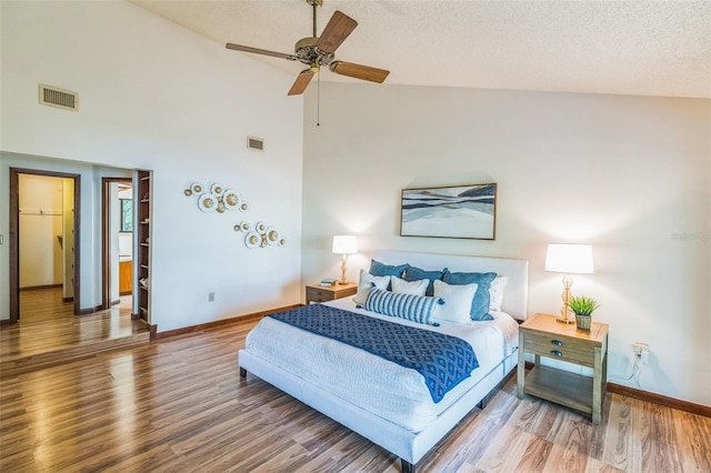 bedroom with hardwood / wood-style flooring, ceiling fan, a textured ceiling, and high vaulted ceiling