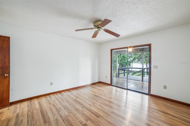 empty room with ceiling fan, light wood-type flooring, and a textured ceiling