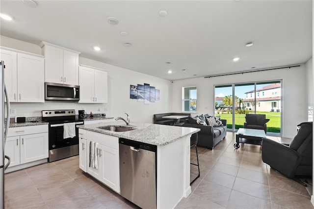 kitchen with white cabinetry, stainless steel appliances, sink, and light stone countertops