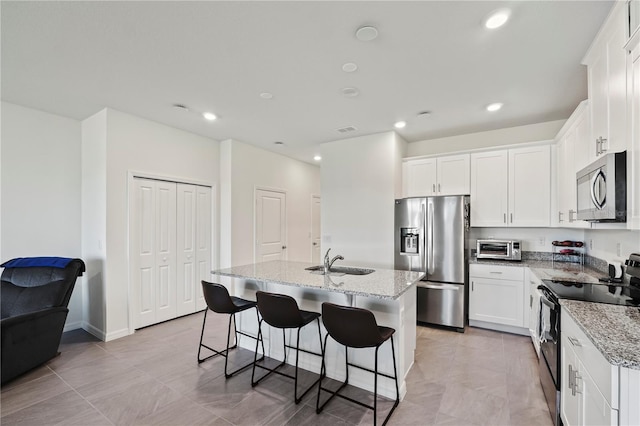 kitchen with white cabinetry, appliances with stainless steel finishes, and an island with sink