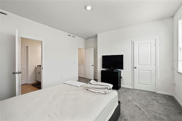 bedroom featuring connected bathroom, a textured ceiling, and carpet floors