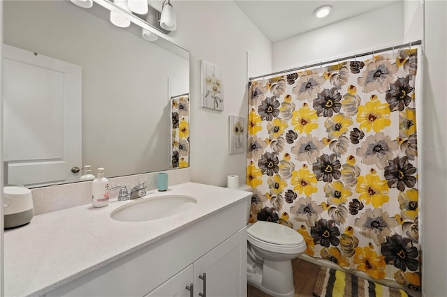 bathroom with walk in shower, vanity, and toilet