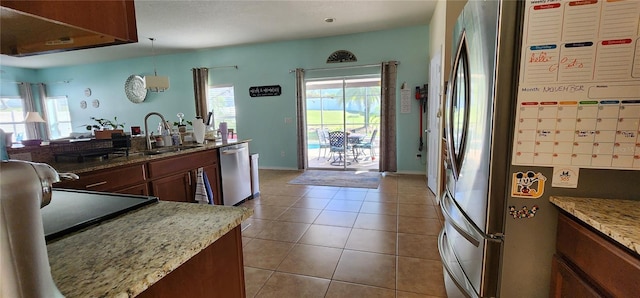 kitchen featuring light stone countertops, pendant lighting, stainless steel appliances, and a wealth of natural light