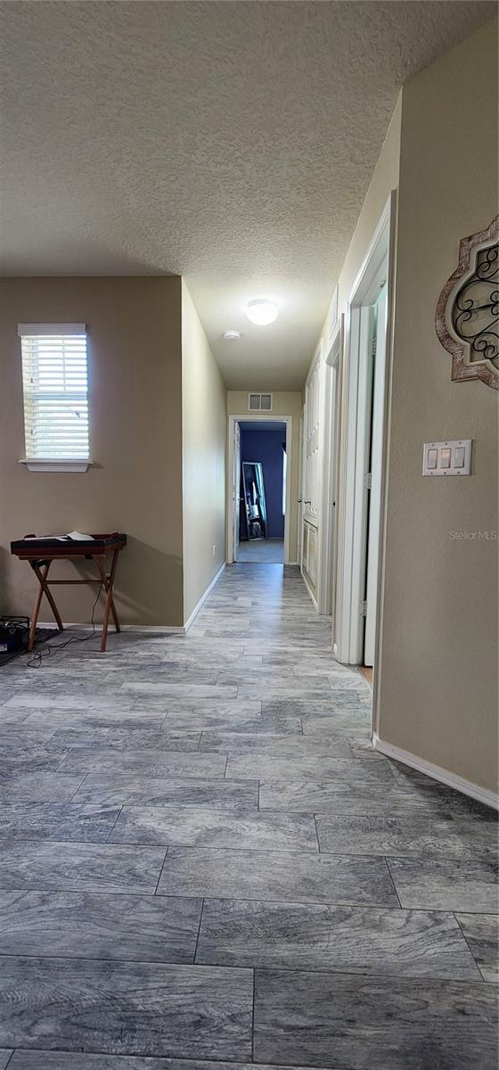 hallway featuring wood-type flooring and a textured ceiling