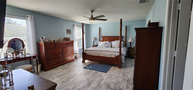 bedroom featuring ceiling fan, light hardwood / wood-style floors, and a textured ceiling