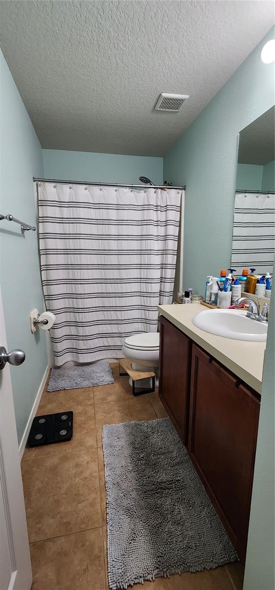 bathroom with tile patterned floors, vanity, a textured ceiling, toilet, and curtained shower