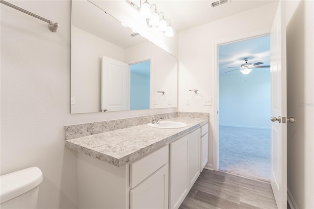 bathroom featuring vanity, hardwood / wood-style flooring, toilet, and ceiling fan