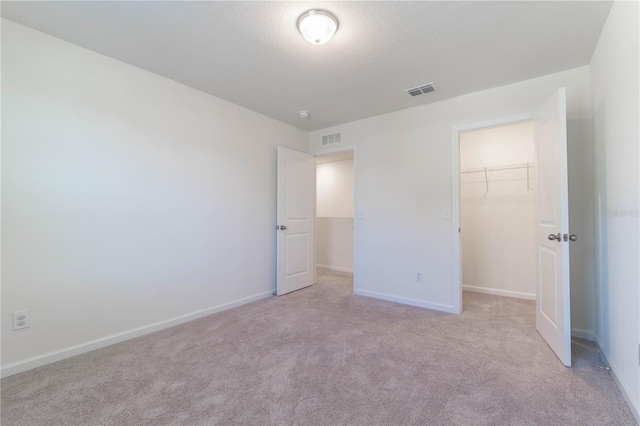 unfurnished bedroom featuring light carpet, a spacious closet, and a closet