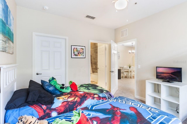 bedroom featuring a chandelier, carpet, and ensuite bath