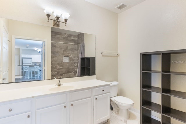 bathroom with vanity, toilet, and tiled shower