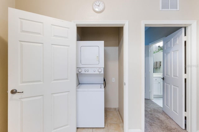 clothes washing area with stacked washer / drying machine and light carpet