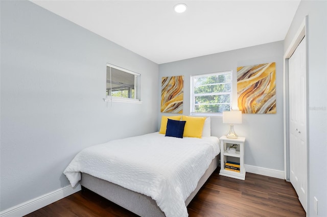 bedroom with wood finished floors, baseboards, and a closet