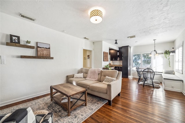 living room with a textured ceiling and dark wood-type flooring