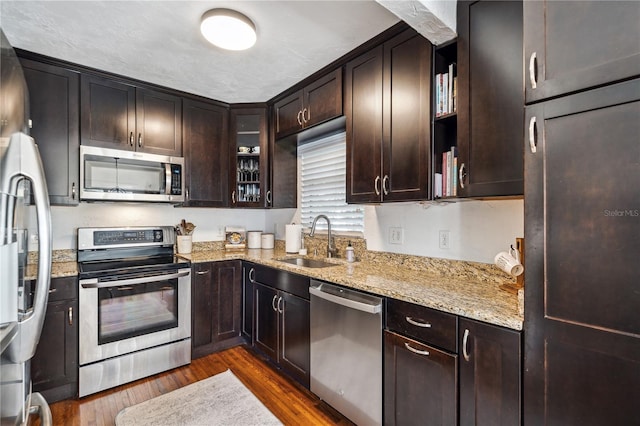 kitchen featuring dark hardwood / wood-style flooring, light stone counters, sink, and stainless steel appliances