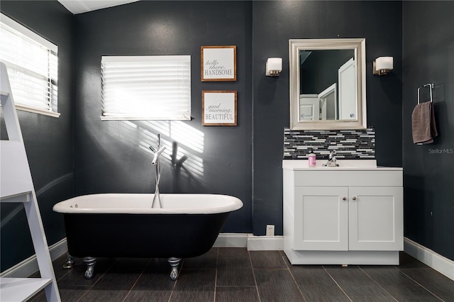 bathroom with backsplash, a washtub, vanity, and lofted ceiling