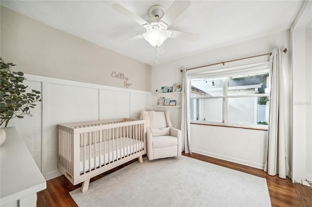 bedroom with ceiling fan, dark hardwood / wood-style flooring, and a crib