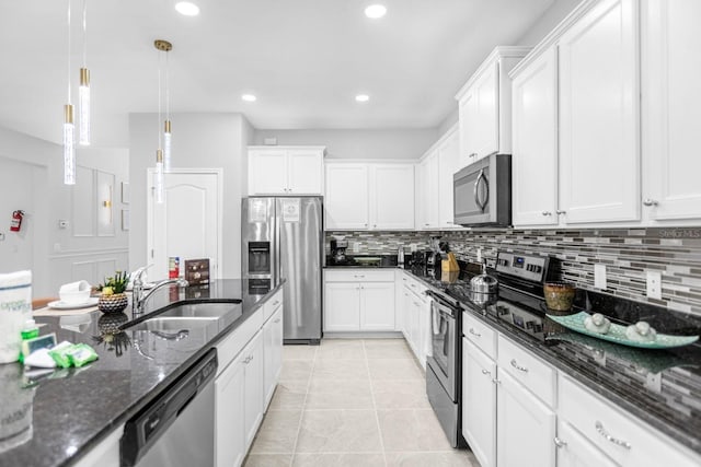 kitchen with pendant lighting, stainless steel appliances, dark stone countertops, and sink