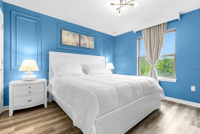 bedroom with a notable chandelier and wood-type flooring