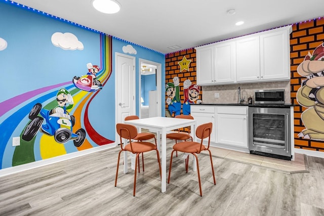 kitchen with backsplash, beverage cooler, sink, white cabinets, and light hardwood / wood-style floors