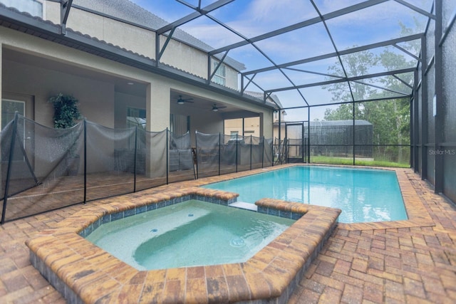 view of pool with glass enclosure, an in ground hot tub, ceiling fan, and a patio