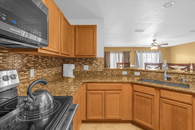 kitchen featuring appliances with stainless steel finishes, backsplash, dark stone counters, sink, and light tile patterned flooring