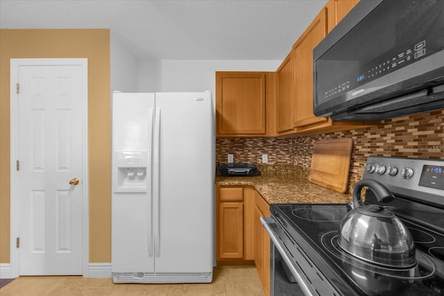 kitchen with decorative backsplash, stainless steel range with electric stovetop, white refrigerator with ice dispenser, light tile patterned floors, and dark stone countertops