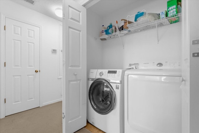 laundry room with separate washer and dryer, light carpet, and a textured ceiling