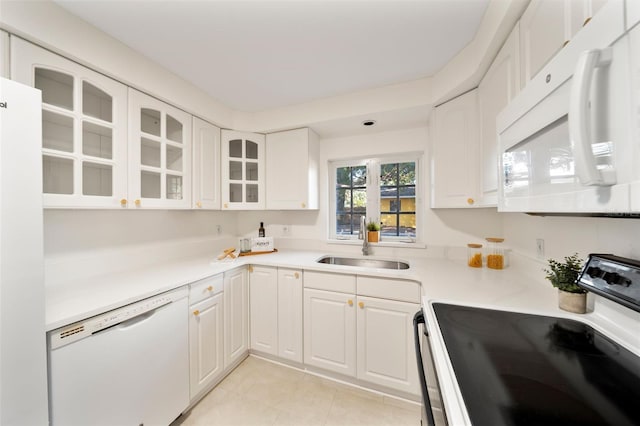 kitchen with white appliances, white cabinets, light tile patterned floors, and sink